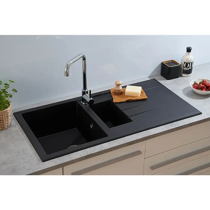 Respekta Einbauspüle Houston - 100 x 50 cm, Anzahl Becken: 1,5 Stk. - Schwarze Doppelspüle mit Abtropffläche, Armatur, Spülbürste, Seife, Behälter, Ölflasche und Erdbeeren auf einer Küchentheke.