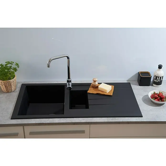 Respekta Einbauspüle Houston - 100 x 50 cm, Anzahl Becken: 1,5 Stk. - Eine moderne schwarze Küchenspüle mit Abtropffläche, Armatur, Spülutensilien und Erdbeeren auf einer hellen Arbeitsplatte.