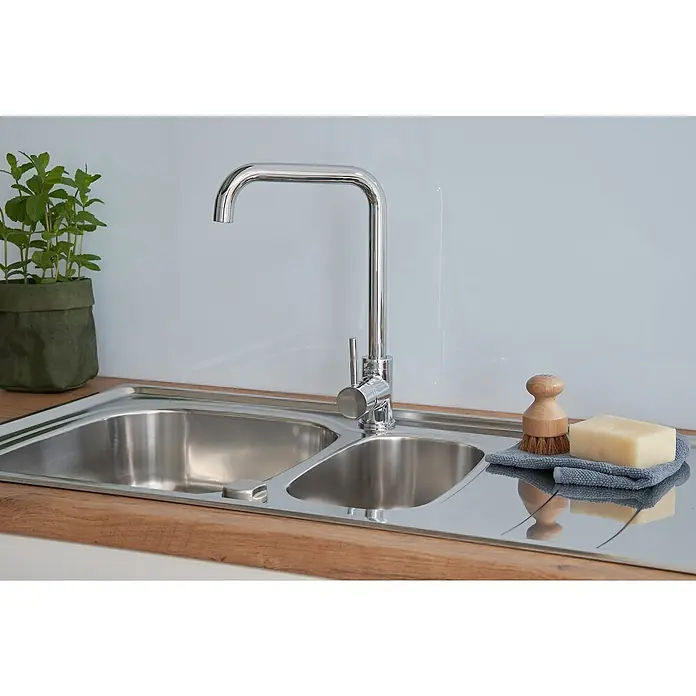Respekta Einbauspüle Miami - 100 x 50 cm, Edelstahl - Spültisch mit Doppelbecken, Armatur, Spülbürste, Seife und einem kleinen Topf mit grünen Kräutern auf einer hölzernen Arbeitsplatte.