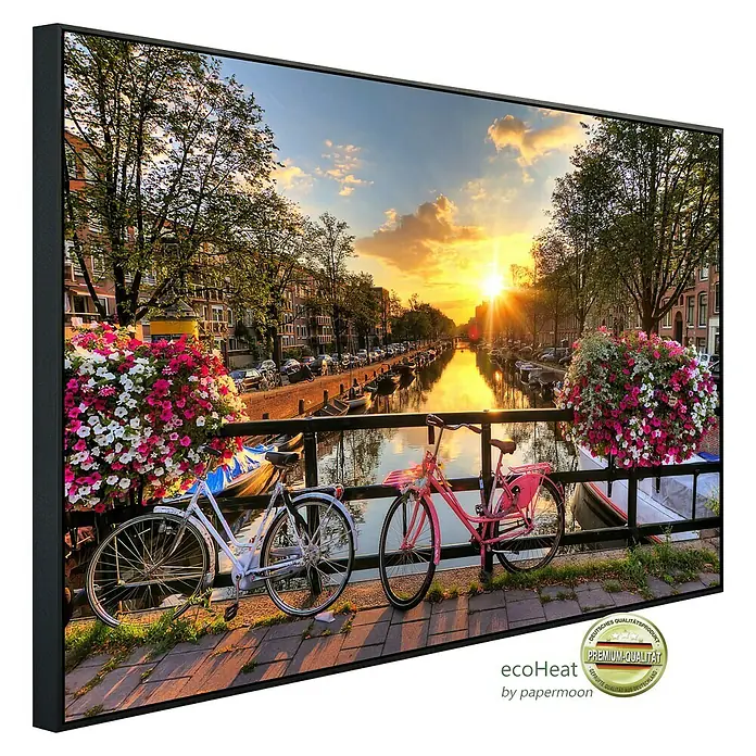 Papermoon Infrarot-Bildheizkörper Amsterdam Sonnenaufgang - 60 cm x 500 mm, 350 W - Das gerahmte Wandbild zeigt eine malerische Szene eines Amsterdamer Kanals mit Fahrrädern, eingefangen bei Sonnenuntergang.