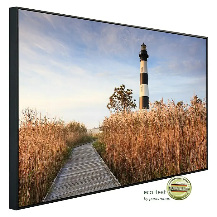 Papermoon Infrarot-Bildheizkörper Bodie Island Leuchtturm - 90 cm x 500 mm, 450 W - Gerahmtes Wandbild mit Leuchtturm-Motiv. Das Bild zeigt einen Weg durch hohes Gras zu einem schwarz-weiß gestreiften Leuchtturm unter blauem Himmel.