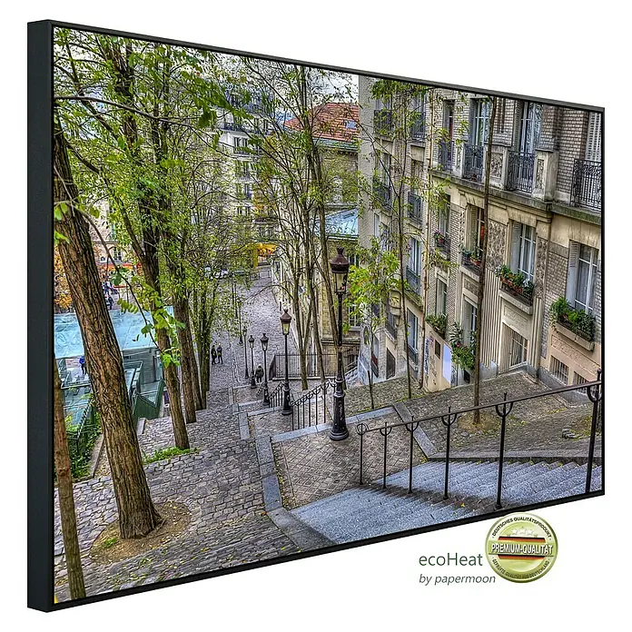 Papermoon Infrarot-Bildheizkörper Montmartre in Paris - 120 cm x 600 mm, 1.000 W - Schwarz gerahmtes Bild mit einer malerischen Treppe in Paris, die von Bäumen und Häusern gesäumt ist und eine ruhige Atmosphäre vermittelt.