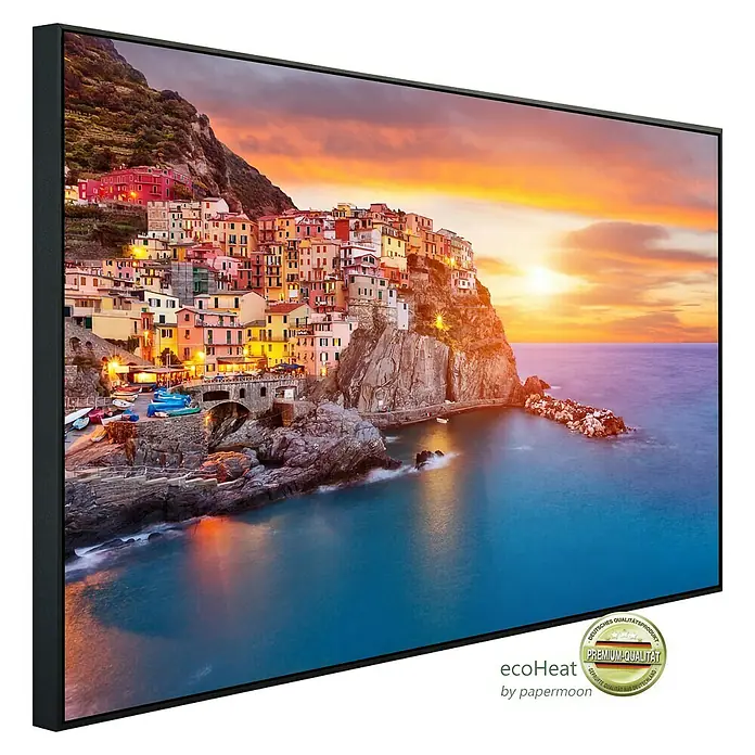 Papermoon Infrarot-Bildheizkörper Manarola Cinque Terre Küste - 100 x 60 cm, 600 W - Das Leinwandbild zeigt eine Küstenstadt bei Sonnenuntergang, eingerahmt in einem eleganten, schwarzen Rahmen.