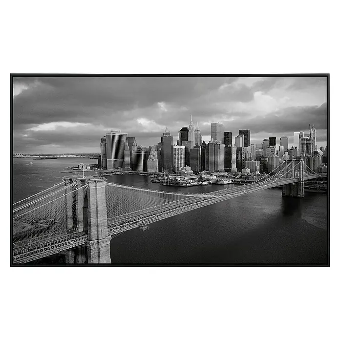 Papermoon Infrarot-Bildheizkörper Brooklyn Bridge schwarz / weiss - 90 cm x 500 mm, 450 W - Schwarz-Weiß-Foto der Brooklyn Bridge, die sich vor der Skyline von New York City erstreckt, gerahmt in einem eleganten schwarzen Rahmen.