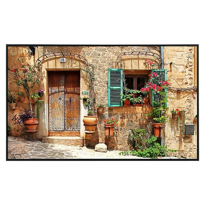 Papermoon Infrarot-Bildheizkörper Charmante Straße - 120 cm x 600 mm, 1.000 W - Einladender Hauseingang mit Holztür, Fenster mit grünen Fensterläden und üppigen Blumenkästen. Eine idyllische Szene mit rustikalem Charme.