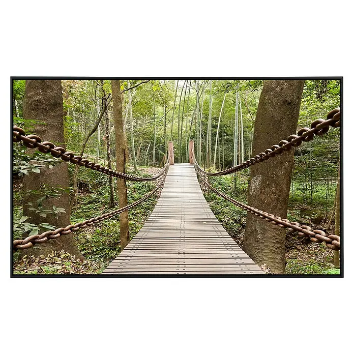 Papermoon Infrarot-Bildheizkörper Hängebrücke - 100 cm x 600 mm, 800 W - Eine malerische Hängebrücke mit Ketten als Geländer führt durch einen üppigen Wald. Die Holzplanken laden zum Überqueren ein.