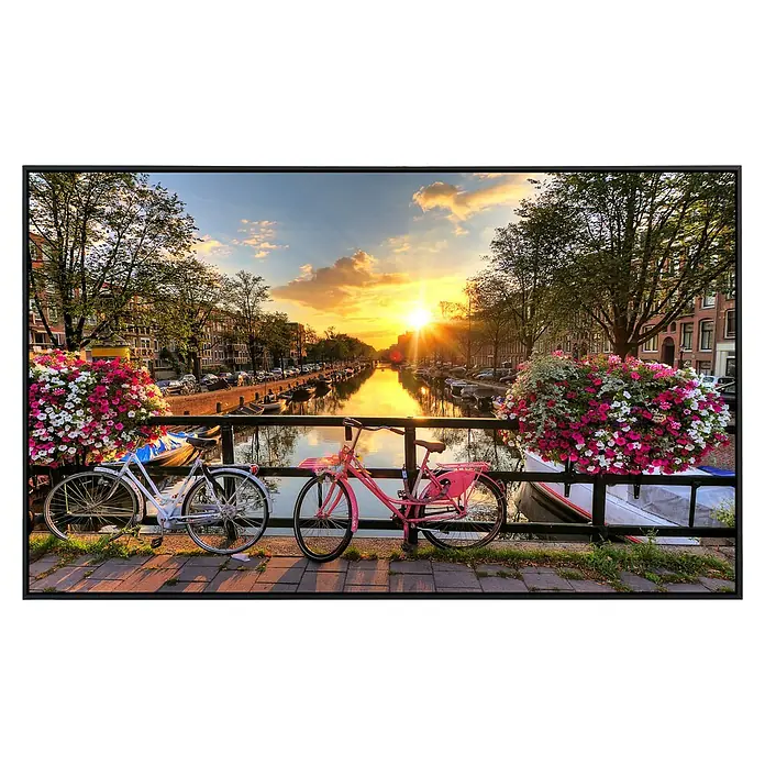Papermoon Infrarot-Bildheizkörper Amsterdam Sonnenaufgang - 60 cm x 500 mm, 350 W - Blick auf eine romantische Szene in Amsterdam mit Fahrrädern, Blumen und einem Kanal bei Sonnenuntergang, gerahmt in einem stilvollen schwarzen Rahmen.