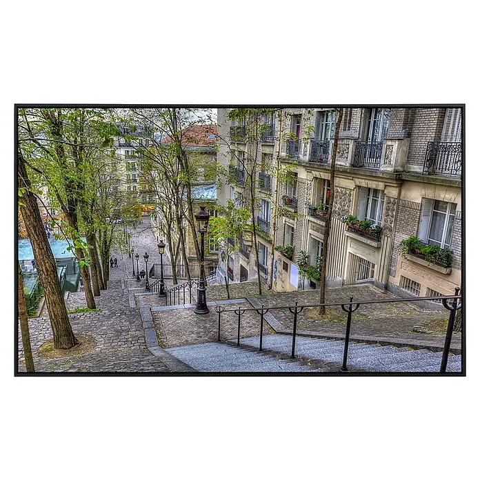 Papermoon Infrarot-Bildheizkörper Montmartre in Paris - 120 cm x 600 mm, 1.000 W - Eine malerische Treppe in Montmartre, Paris, gesäumt von Bäumen und historischen Gebäuden, die den Charme des Viertels widerspiegelt.