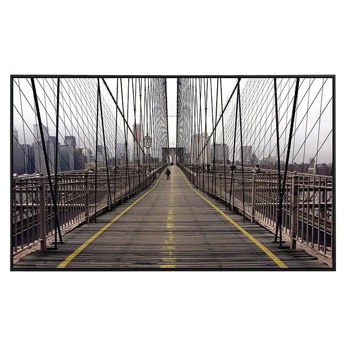 Papermoon Infrarot-Bildheizkörper Brookly Bridge - 100 x 60 cm, 600 W - Blick über die Brooklyn Bridge mit gelben Linien und einem einsamen Fußgänger in der Mitte des Weges mit Stadt im Hintergrund.