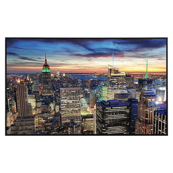 Papermoon Infrarot-Bildheizkörper New York in der Abenddämmerung - 100 x 60 cm, 800 W - Darstellung eines modernen Fernsehers, der ein lebendiges Stadtbild von New York bei Nacht zeigt, mit leuchtenden Wolkenkratzern und klarem Display.