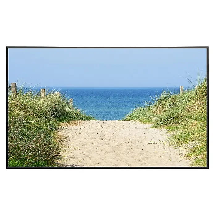 Papermoon Infrarot-Bildheizkörper Düne am Ozean - 100 x 60 cm, 600 W - Sandweg zum Meer mit Dünenlandschaft, eingefasst in einem schwarzen Rahmen. Ein idyllisches Küstenmotiv mit hellem Sand und blauem Wasser.