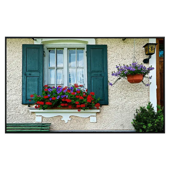 Papermoon Infrarot-Bildheizkörper Bayerisches Fenster - 60 x 50 cm, 350 W - Ein Fenster mit blaugrünen Fensterläden und einem Blumenkasten mit roten und lila Blumen, das Gebäude ist mit einer Lampe und einem Topf verziert.