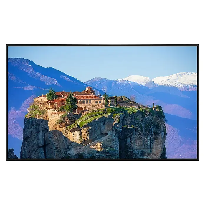 Papermoon Infrarot-Bildheizkörper Kloster der Heiligen Dreifaltigkeit - 120 x 60 cm, 1.000 W - Ein auf einem Felsen gelegenes Kloster mit rotem Dach und Blick auf schneebedeckte Berge, präsentiert als Fernsehbildschirm.