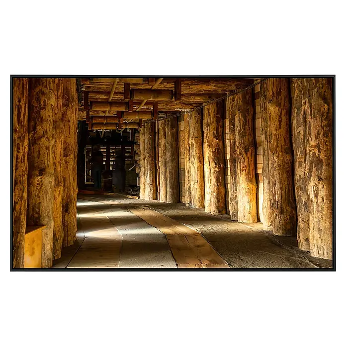 Papermoon Infrarot-Bildheizkörper Salzbergwerk Wieliczka - 100 x 60 cm, 600 W - Das Foto zeigt einen unterirdischen Tunnel, verstärkt mit Holzstämmen, der ein Gefühl von Tiefe und struktureller Integrität vermittelt.