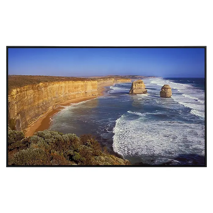Papermoon Infrarot-Bildheizkörper Große Ocean Road - 120 x 60 cm, 1.000 W - Bild von den Zwölf Aposteln, einer Kalksteinformation in Australien, das Meer, Sandstrände und Küstenklippen in einem schwarzen Rahmen zeigt.
