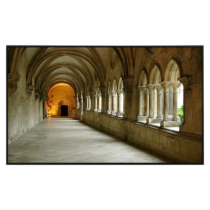 Papermoon Infrarot-Bildheizkörper Batalhakloster120 x 90 cm, 1.200 W - Blick durch den Kreuzgang mit eleganten Bögen und Säulen, die das Licht auf den Boden reflektieren und ein Gefühl von Geschichte und Erhabenheit vermitteln.