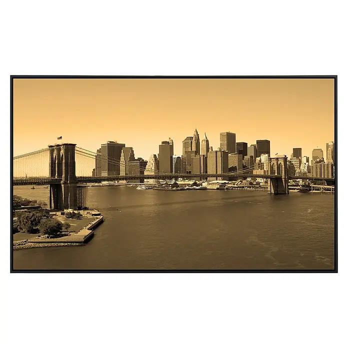 Papermoon Infrarot-Bildheizkörper Brooklyn - 120 cm x 600 mm, 1.000 W - Sepiafarbenes Foto der Skyline von New York City mit der Brooklyn Bridge im Vordergrund, gerahmt in einem modernen schwarzen Rahmen.