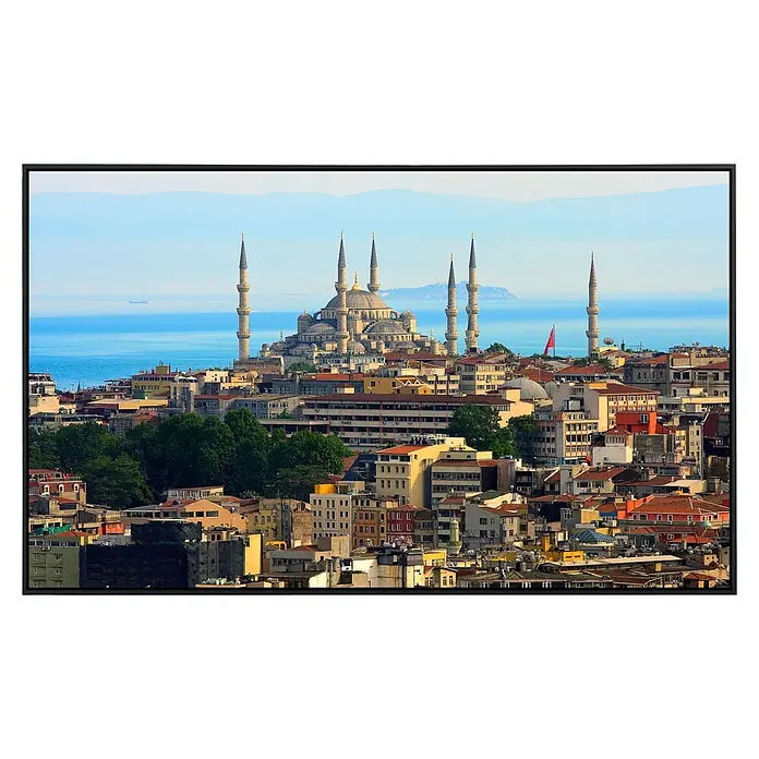 Papermoon Infrarot-Bildheizkörper Istanbul Skyline - 100 x 60 cm, 600 W - Luftaufnahme der Blauen Moschee in Istanbul, Türkei, mit Blick auf die Stadt und das Meer bei blauem Himmel, gerahmt mit einem schwarzen Rahmen.