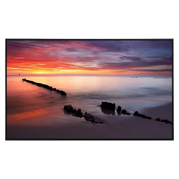 Papermoon Infrarot-Bildheizkörper Baltischer Sonnenaufgang - 100 x 60 cm, 800 W - Ein atemberaubendes Gemälde eines Sonnenuntergangs am Meer mit Holzpfählen, eingefasst in einem eleganten schwarzen Rahmen.