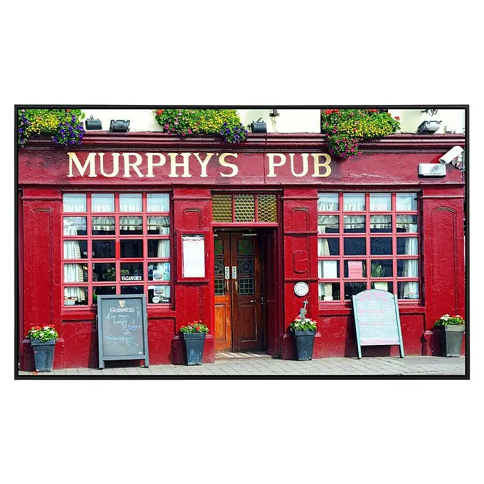 Papermoon Infrarot-Bildheizkörper Murphys Pub Dingle Bay - 100 x 60 cm, 600 W - Das Foto zeigt die Fassade von Murphy's Pub mit leuchtend roter Farbe, Fenstern und Blumenkästen.