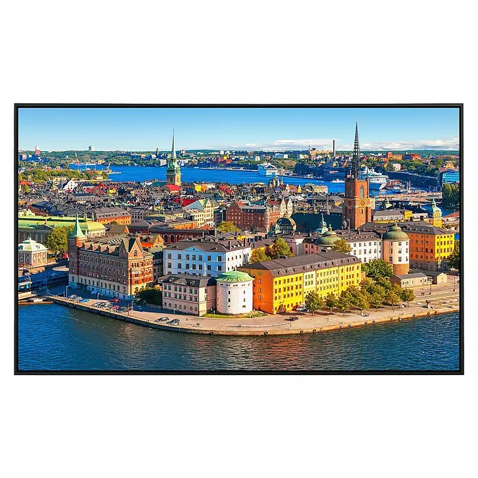 Papermoon Infrarot-Bildheizkörper Stockholmer Altstadt - 120 x 60 cm, 1.200 W - Ein hochauflösender Fernseher zeigt ein lebendiges Stadtbild mit bunten Gebäuden, blauen Wasserwegen und klarem Himmel.