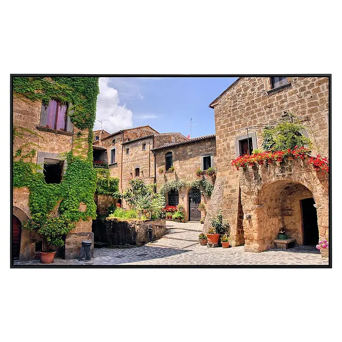 Papermoon Infrarot-Bildheizkörper Italienisches altes Dorf - 60 x 50 cm, 350 W - Malerische Gasse in einer italienischen Stadt mit alten Steinhäusern, üppigem Grün und blühenden Blumen, die eine idyllische Atmosphäre schaffen.