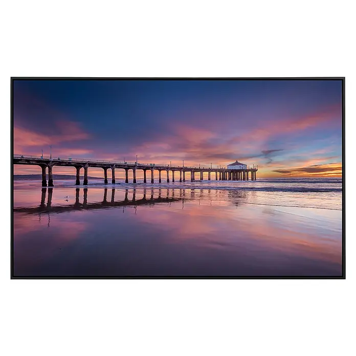 Papermoon Infrarot-Bildheizkörper Pier bei Sonnenuntergang - 100 x 60 cm, 800 W - Ein atemberaubender Blick auf eine Seebrücke bei Sonnenuntergang, gerahmt von einem modernen schwarzen Rahmen, der die warmen Farbtöne hervorhebt.