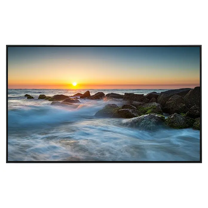 Papermoon Infrarot-Bildheizkörper St. Augustine Ocean Beach - 120 x 60 cm, 1.000 W - Sonnenaufgang am Strand mit Felsen, umrahmt von einem schwarzen Rahmen, ideal für eine stimmungsvolle Wanddekoration.