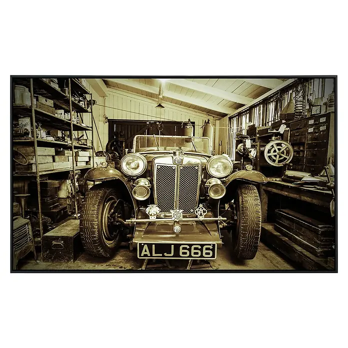 Papermoon Infrarot-Bildheizkörper Vintage Sportwagen - 60 x 50 cm, 350 W - Nahaufnahme eines Oldtimer-MG, Kennzeichen ALJ 666, geparkt in einer Werkstatt voller Werkzeuge und Regale.
