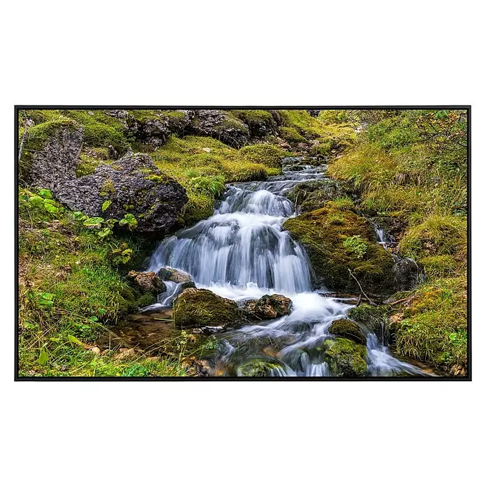 Papermoon Infrarot-Bildheizkörper Gebirgsbach in den Dolomiten - 60 x 50 cm, 350 W - Ein kleiner Wasserfall stürzt über moosbewachsene Felsen, umgeben von üppiger grüner Vegetation in einer Naturlandschaft.