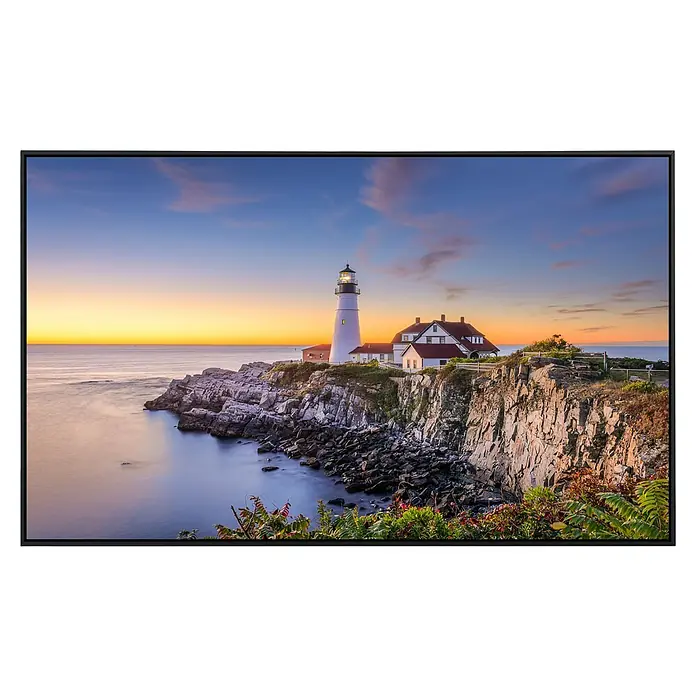 Papermoon Infrarot-Bildheizkörper Leuchtturm Portland Main - 60 x 50 cm, 350 W - Natur trifft Technik: Ein moderner Fernseher zeigt ein idyllisches Küstenbild mit Leuchtturm bei Sonnenuntergang in lebendigen Farben.