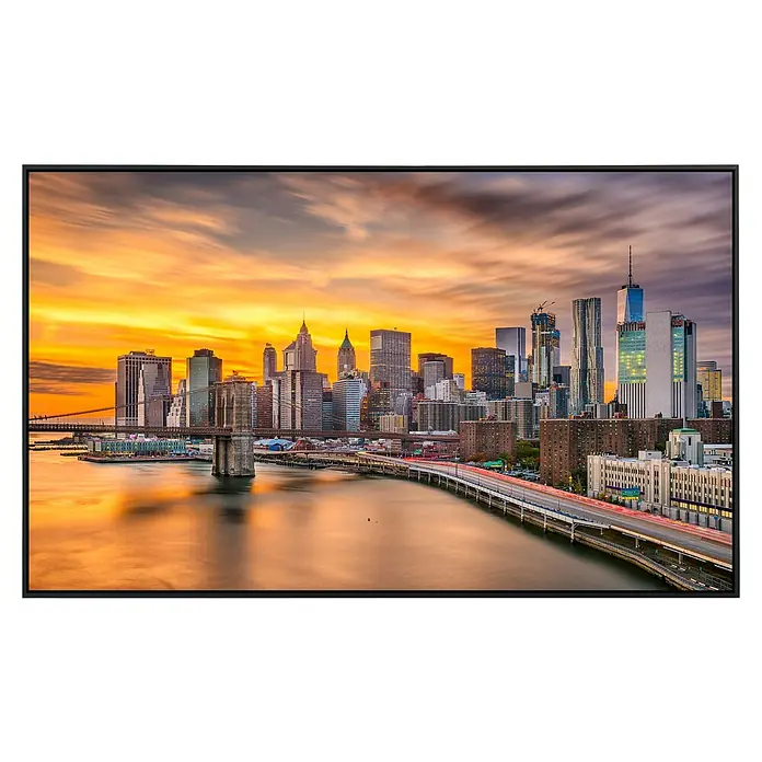 Papermoon Infrarot-Bildheizkörper Manhattan Skyline Sonnenuntergang - 120 x 60 cm, 1.200 W - Ein TV-Gerät zeigt ein lebhaftes Stadtbild von New York bei Sonnenuntergang, mit der Brooklyn Bridge im Vordergrund.