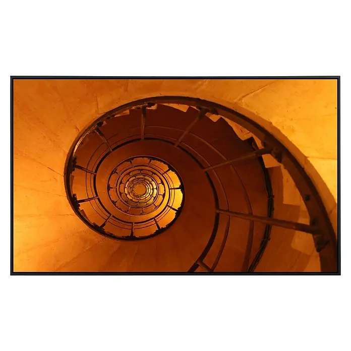 Papermoon Infrarot-Bildheizkörper Wendeltreppe - 1.000 x 600 mm, 600 W - Blick von oben auf eine Wendeltreppe, die sich spiralförmig nach unten windet. Warmes Licht betont die architektonische Form.