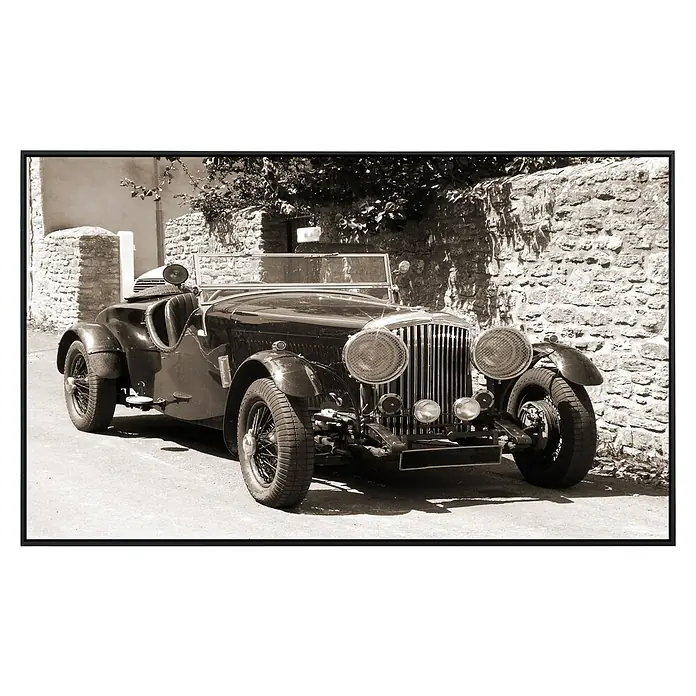 Papermoon Infrarot-Bildheizkörper Oldtimer 1 - 1.000 x 600 mm, 600 W - Schwarz-Weiß-Foto eines klassischen Bentley-Sportwagens, der auf einer Straße vor einer Steinmauer parkt, eingefangen in elegantem Vintage-Stil.