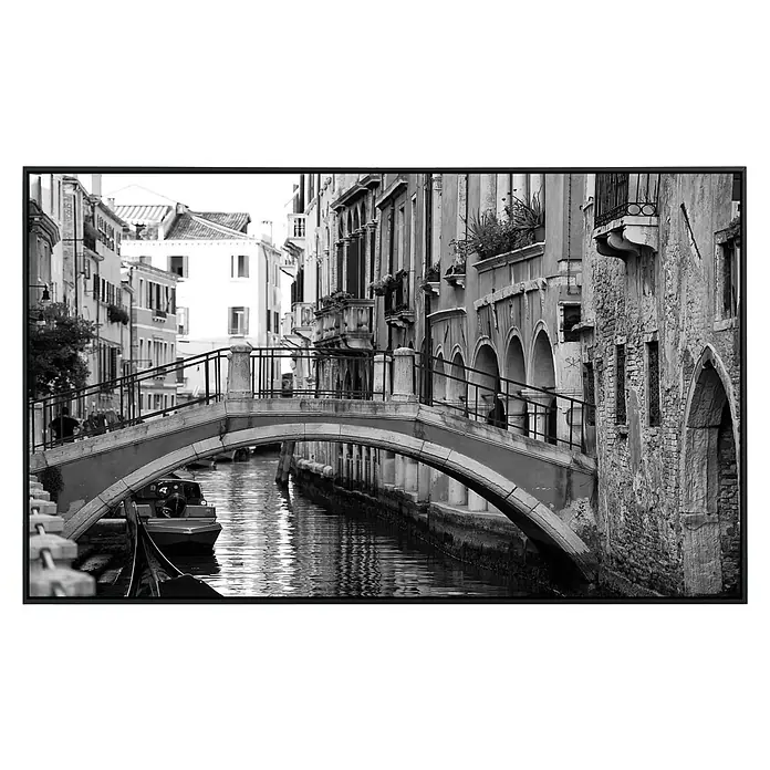 Papermoon Infrarot-Bildheizkörper Venedig Brücke - 100 x 60 cm, 600 W - Schwarze und weiße Aufnahme einer ruhigen venezianischen Wasserstraße mit einer malerischen Steinbrücke und Booten.