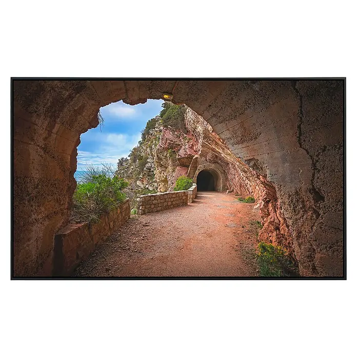 Papermoon Infrarot-Bildheizkörper Felsentunnel Petrovac Bay - 100 x 60 cm, 800 W - Ein Tunnel mit grober Textur, die sich durch eine felsige Küstenlinie schlängelt und einen einzigartigen Einblick in das Innere der Erde bietet.
