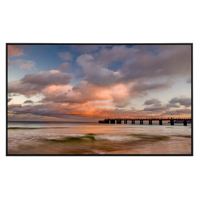 Papermoon Infrarot-Bildheizkörper Porto Santo Pier Sonnenuntergang - 90 x 50 cm, 450 W - Malerische Aufnahme einer Küstenlandschaft bei Sonnenuntergang mit einem langen Pier, der ins Meer ragt und von Wolken umrahmt wird.