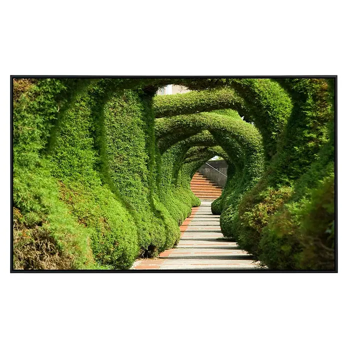 Papermoon Infrarot-Bildheizkörper Wacholder - 120 x 60 cm, 1.000 W - Grüner Tunnelblick: Ein Weg führt durch einen üppigen, grünen Tunnel, der durch kunstvoll geschnittene Büsche und Sträucher geformt wurde.