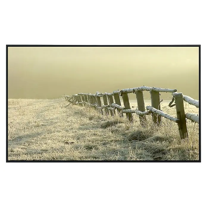 Papermoon Infrarot-Bildheizkörper Zaun im nebligen Feld - 100 x 60 cm, 800 W - Raureifbedeckter Zaun: Ein rustikaler Holzzaun, leicht mit Raureif bedeckt, durchquert eine winterliche Landschaft unter einem trüben Himmel.