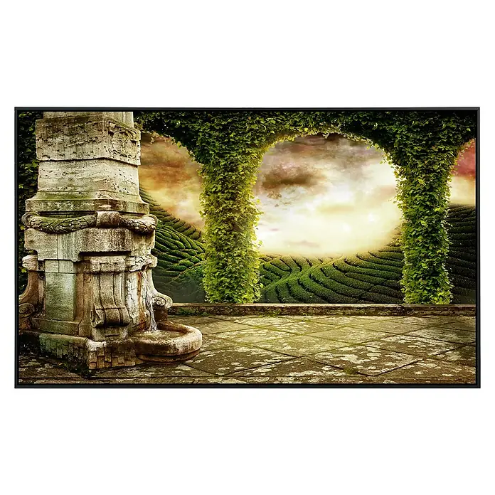 Papermoon Infrarot-Bildheizkörper Mystische Landschaftsansicht - 100 x 60 cm, 800 W - Detailaufnahme eines gerahmten Kunstwerks mit einer Steinfontäne und üppigem Grün, das eine ruhige und fantasievolle Szene darstellt.