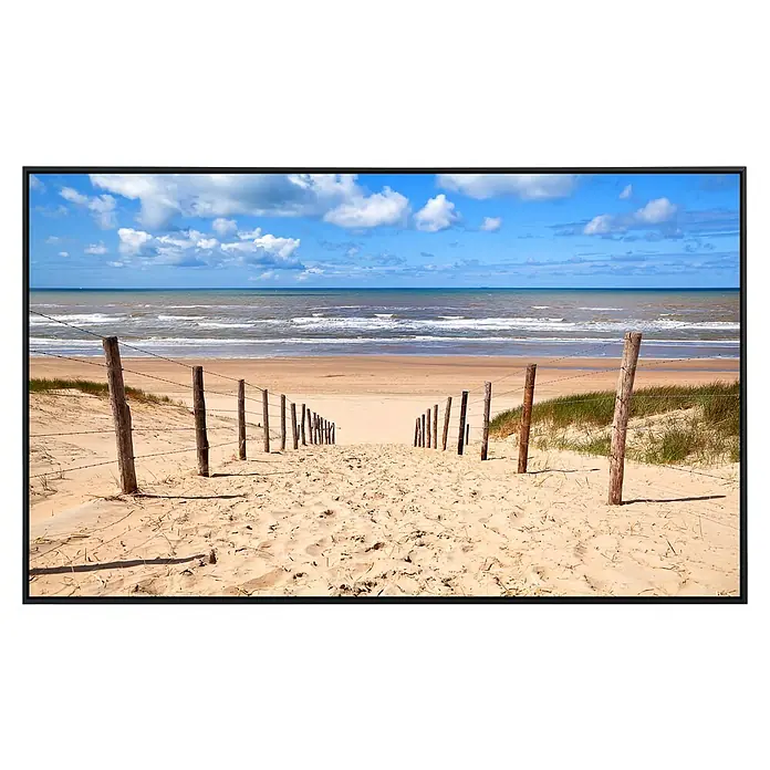 Papermoon Infrarot-Bildheizkörper Weg zum Sandstrand - 90 cm x 500 mm, 450 W - Strandweg mit Holzpfosten und Stacheldraht, der zu Meer unter blauem Himmel mit Wolken führt.