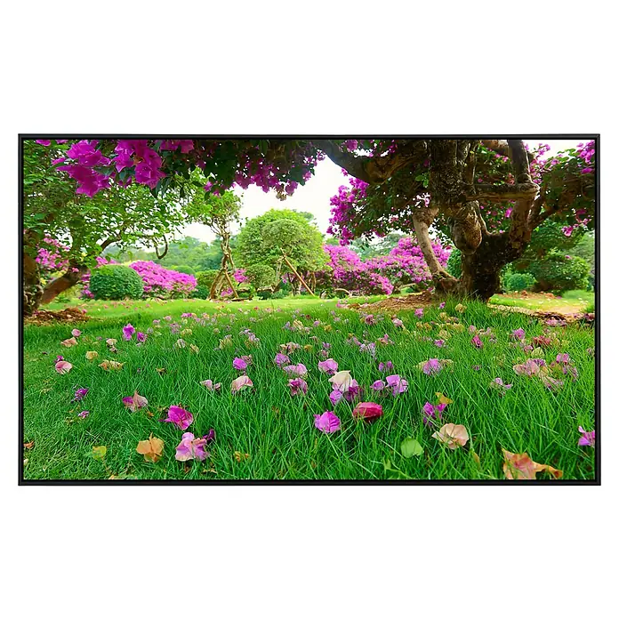Papermoon Infrarot-Bildheizkörper Rasenblumen - 90 x 50 cm, 450 W - Idyllische Gartenlandschaft mit üppiger Blütenpracht und einem grünen Rasen voller verstreuter Blütenblätter unter alten Bäumen.