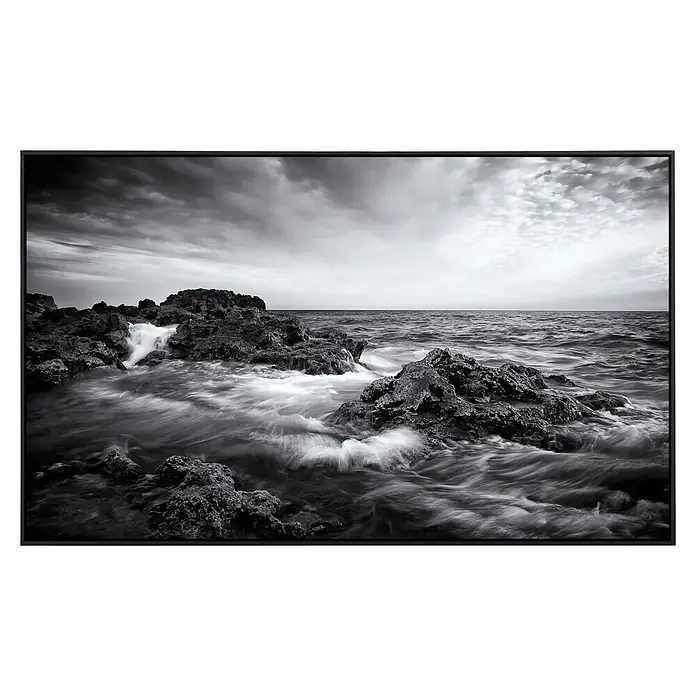 Papermoon Infrarot-Bildheizkörper Seelandschaft mit Wellen - 100 x 60 cm, 800 W - Schwarz-Weiß-Fotografie einer Küstenlinie mit Felsen und fließendem Wasser. Die dynamische Aufnahme fängt die Kraft und Schönheit der Natur ein.