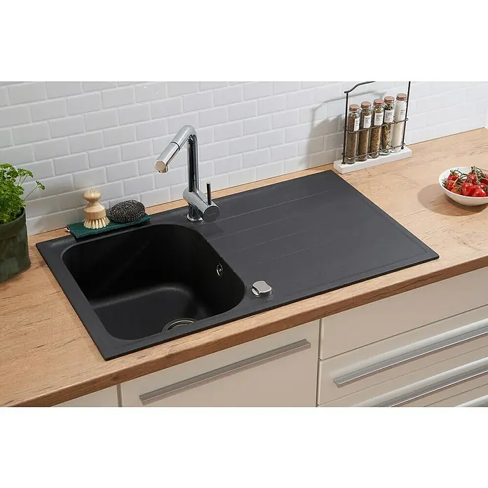 Respekta Fregadero encastrable Orlndo - 86 x 50 cm, Negro - La imagen muestra un fregadero de cocina moderno con escurridor, un grifo y utensilios de cocina sobre una encimera de madera.