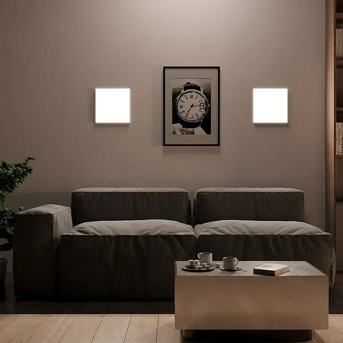 Ledvance SUN@Home LED-Panel Planon Frameless - 20 W, L x B x H: 30 x 30 x 6,1 cm, Weiß, Kaltweiß - Eine moderne Wohnzimmeransicht mit quadratischen Wandleuchten, die ein weiches Licht spenden, und einem bequemen Sofa im Zentrum des Raumes.