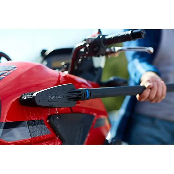 Nilfisk Hochdruckreiniger C 135.7-6 Garden X-tra - 1.500 W, Max. Druck: 135 bar, Fördermenge: 460 l/h - Die Nilfisk Waschbürste wird zur Reinigung eines roten Motorrads verwendet, wobei Wasser abläuft.