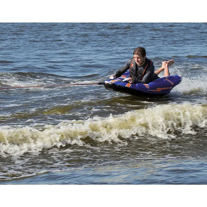Talamex Funtube - 137 x 89 cm, Geeignet für: 1 Person, Schnellbefestigung, Nylon - Ein Mann gleitet auf einem blauen Wassersportgerät mit Blitzdesign über das Wasser und hält sich an Griffen fest. Er trägt eine Schwimmweste.