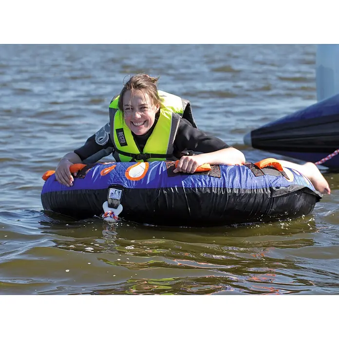 Talamex Funtube Splash - Durchmesser: 138 cm, Geeignet für: 1 Person, Schnellbefestigung - Lachende Frau im Neoprenanzug und Schwimmweste auf einem blauen Tube im Wasser, bereit für Wassersport.