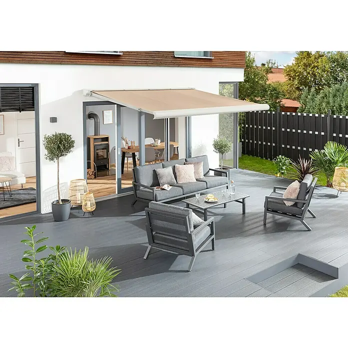 Sunfun Vollkassettenmarkise Elba - Beige, Farbe Gestell: Verkehrsweiß, Breite: 3,5 m, Ausfall: 3 m - Eine stilvolle Terrasse mit einer beigen Markise über einer grauen Loungegarnitur, die Schatten spendet und zum Verweilen einlädt.