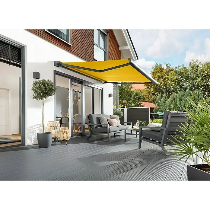 Sunfun Vollkassettenmarkise Elba - Gelb, Farbe Gestell: Anthrazitgrau, Breite: 5 m, Ausfall: 3,5 m - Terrasse mit gelber Markise, grauen Gartenmöbeln und Pflanzen. Die Markise spendet Schatten und sorgt für eine gemütliche Atmosphäre im Freien.
